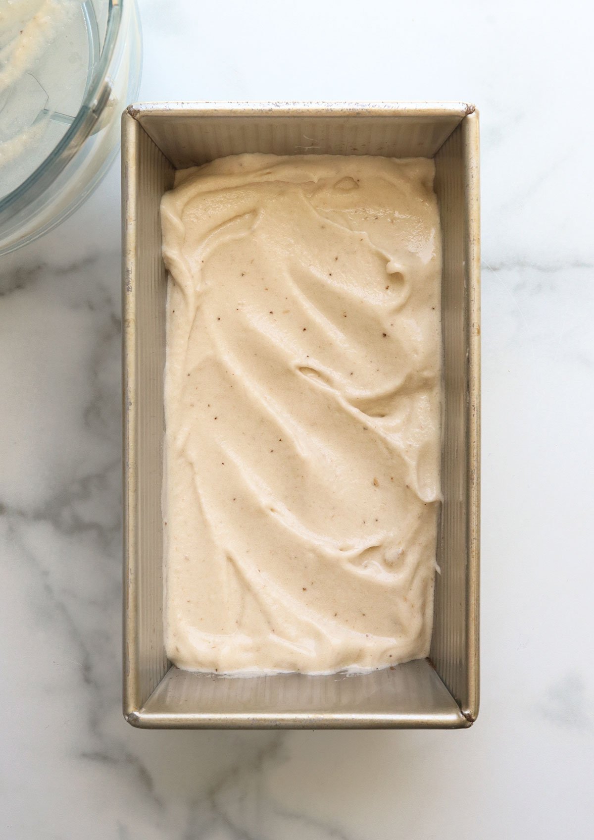 banana ice cream spread into a loaf pan for freezing.
