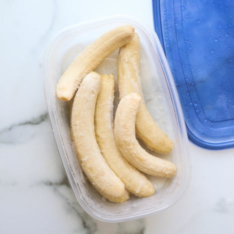 whole bananas frozen in a container with a lid.