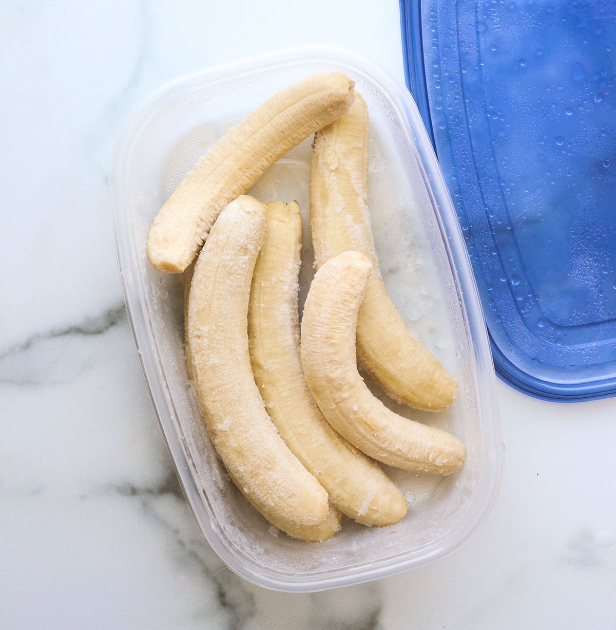 whole bananas frozen in a container with a lid.