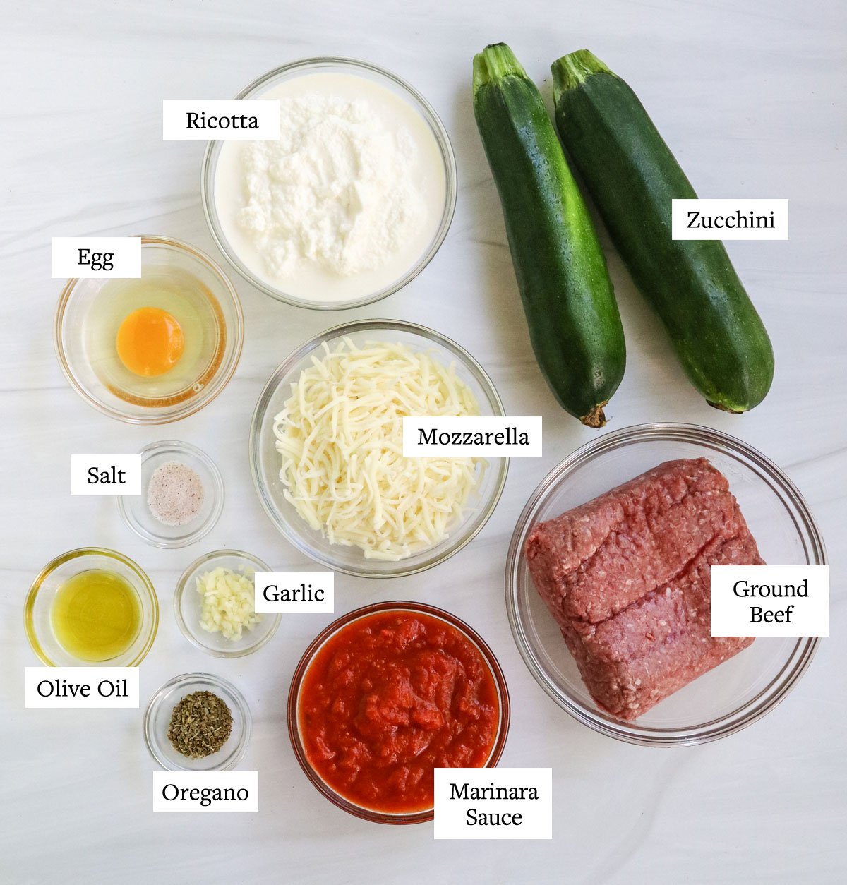 ingredienti per lasagne di zucchine etichettati sulla superficie bianca.