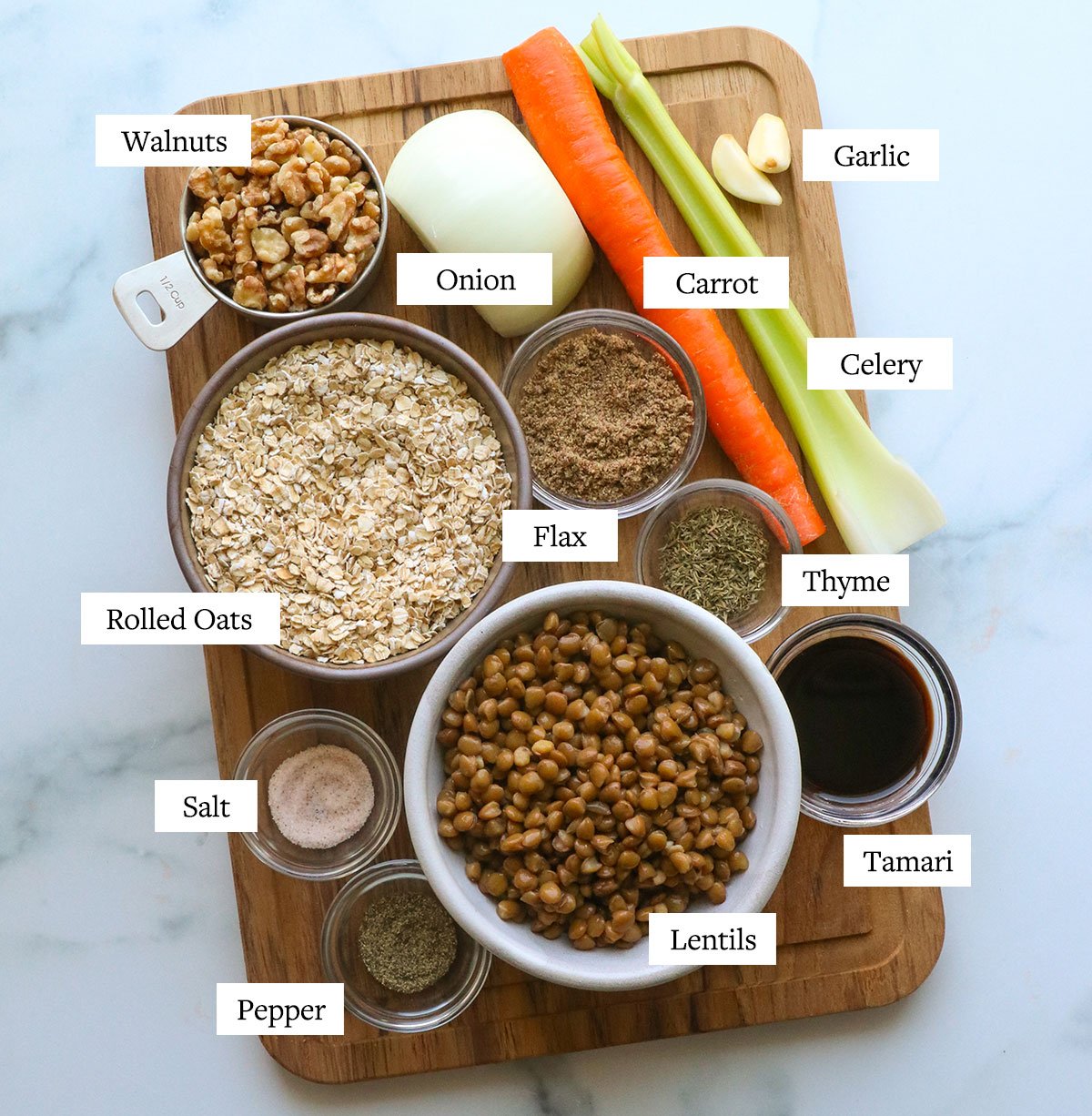 bowls of lentils, oats, ground flax, spices, onion, carrot, and celery on a cutting board. 