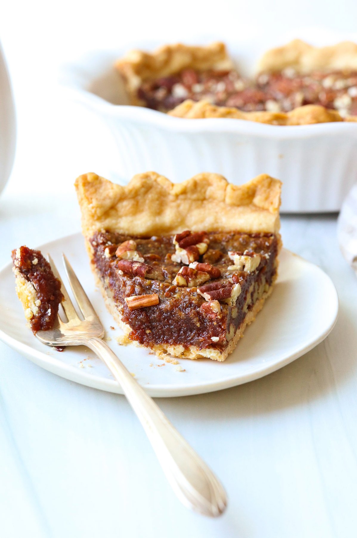 vegan pecan pie slice with bite removed on a fork.