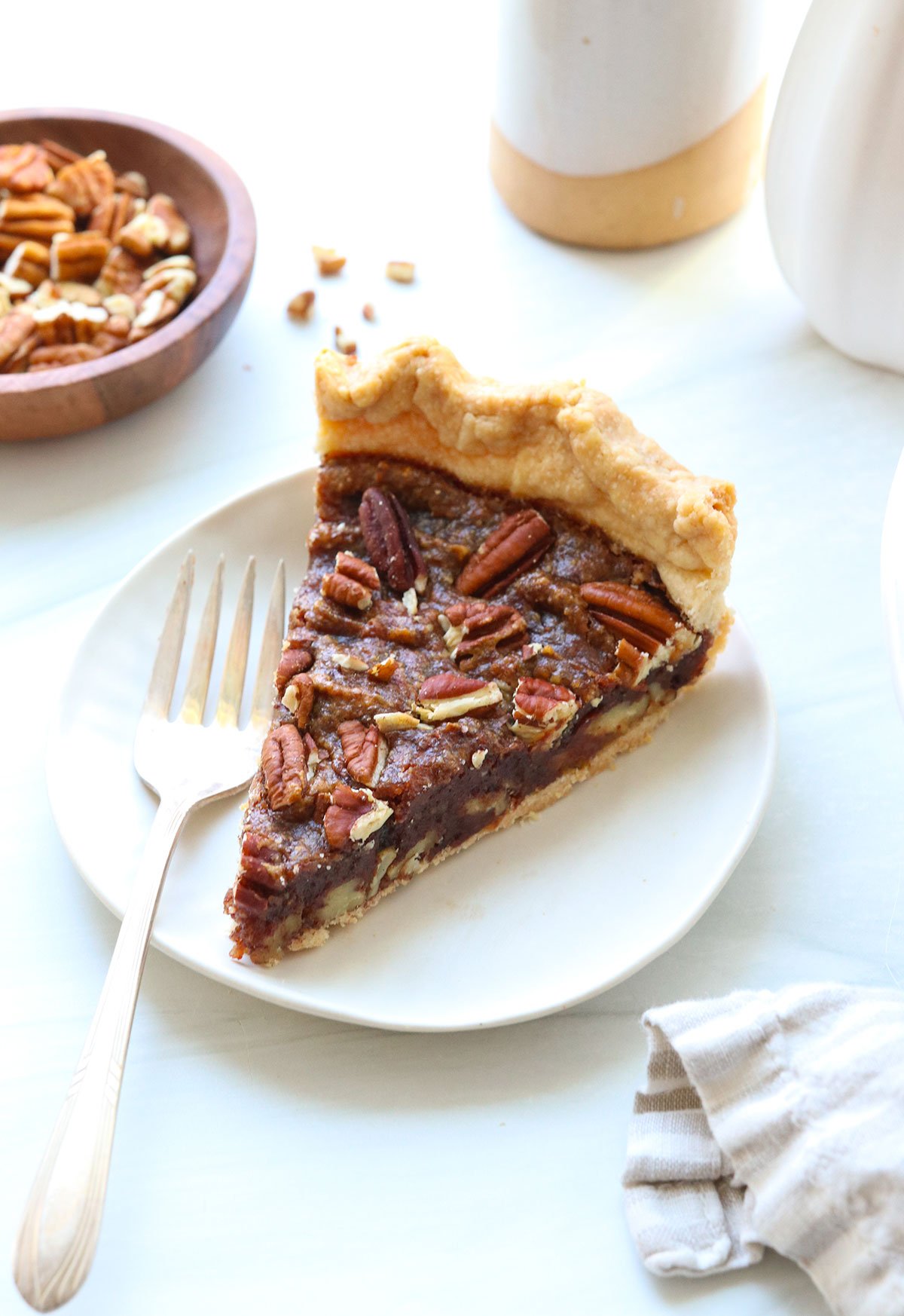 slice of pecan pie on a white plate with a dessert fork.
