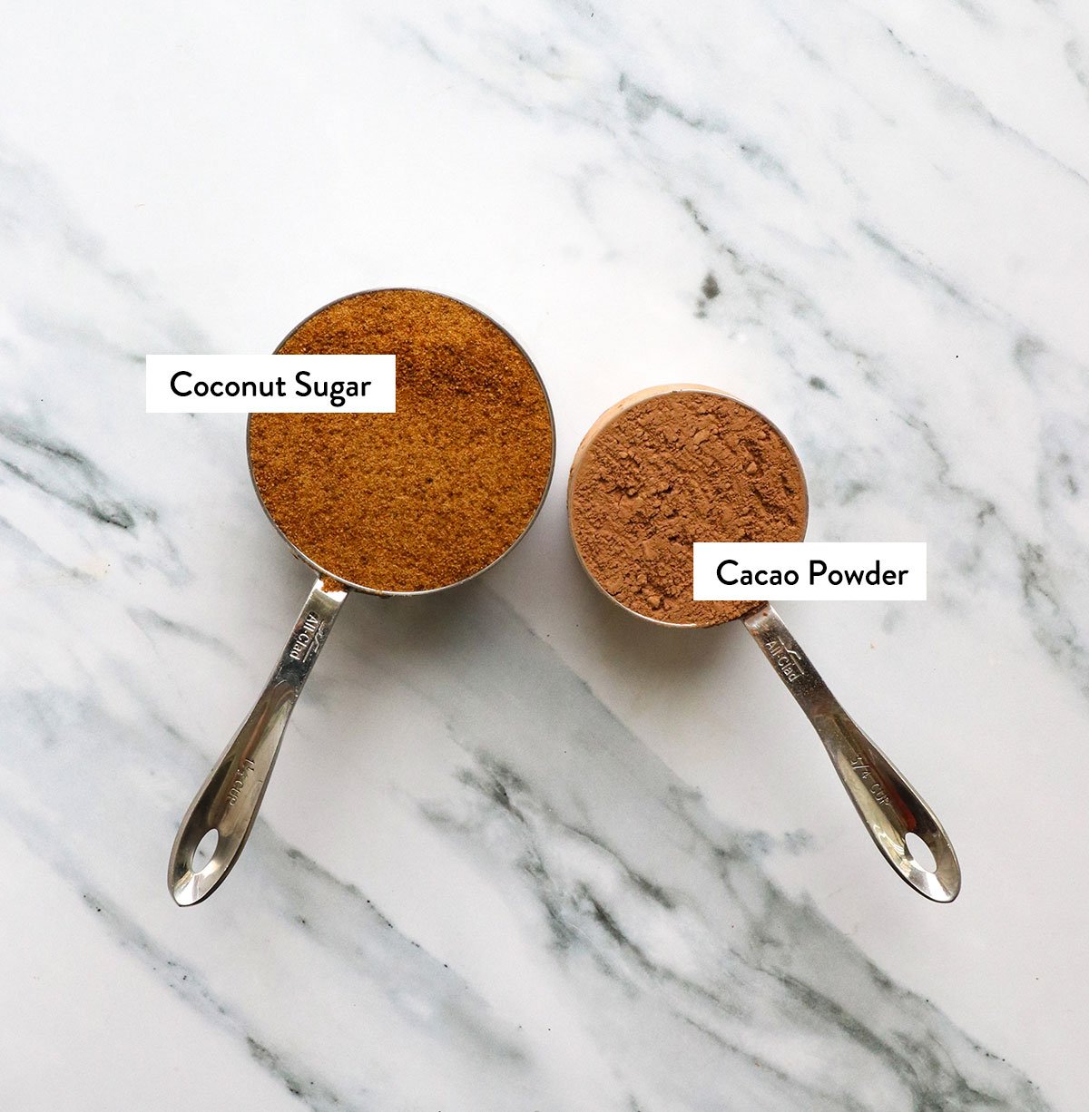 coconut sugar and cacoa powder labeled in two measuring cups. 