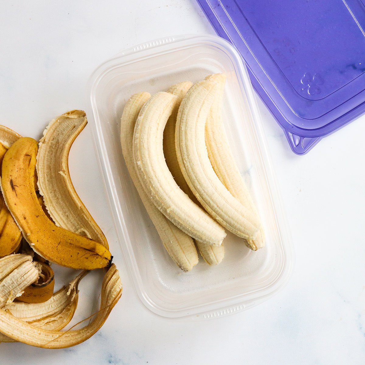 Frozen bananas stored whole in a plastic container.