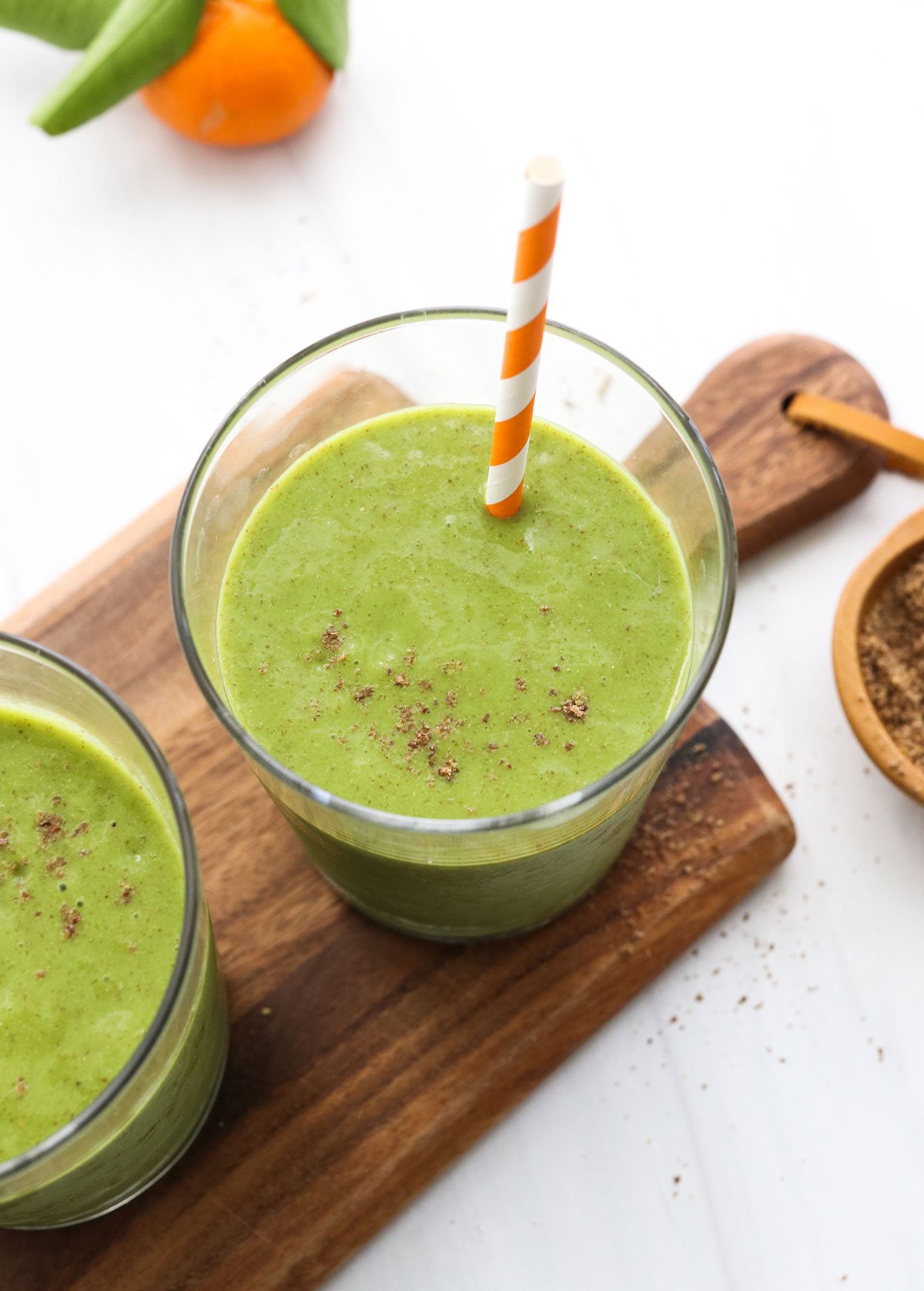 Blended smoothie served in two glasses and topped with ground flax seeds.