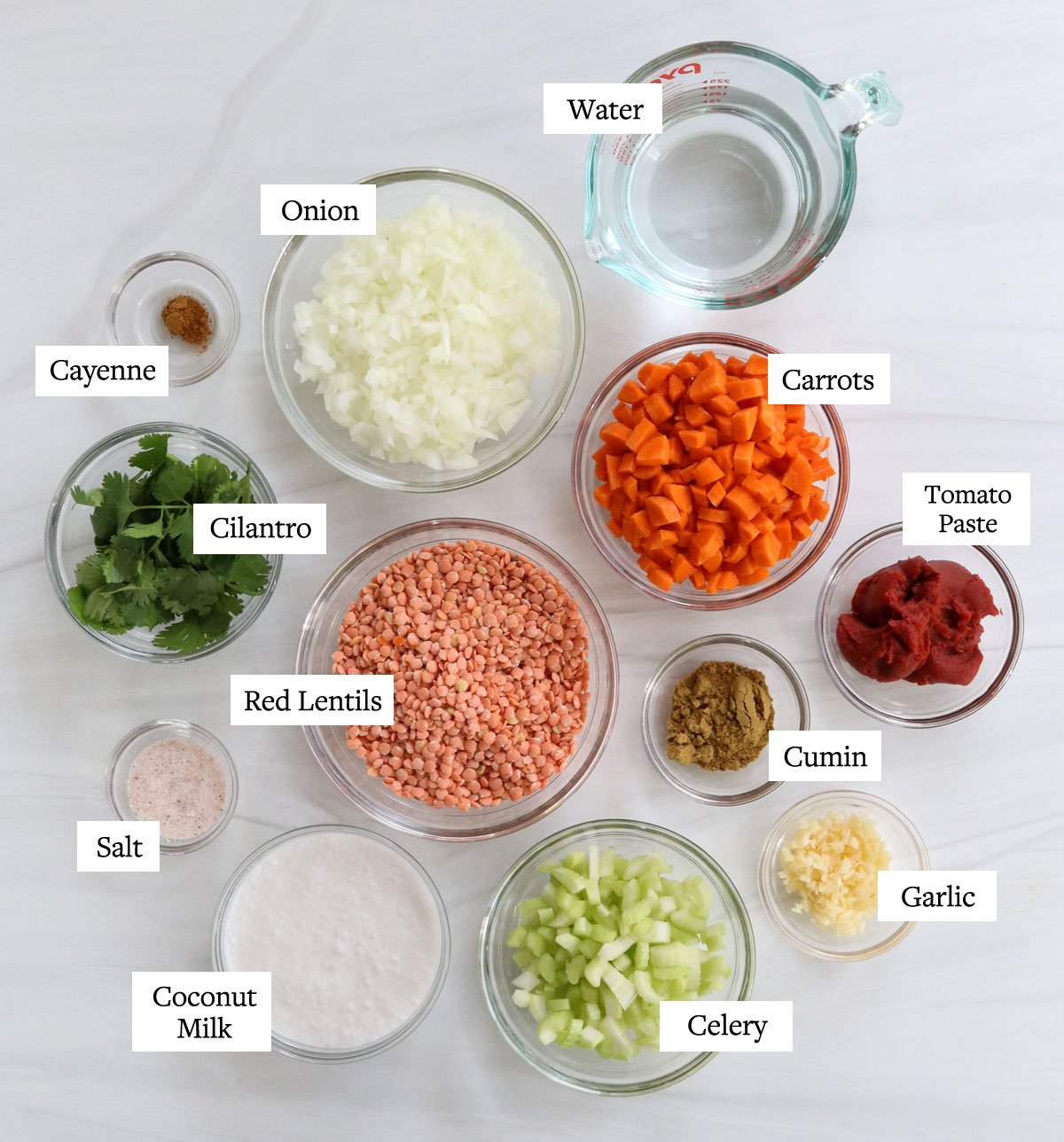 Ingredienti della zuppa di lenticchie rosse etichettati in ciotole di vetro.