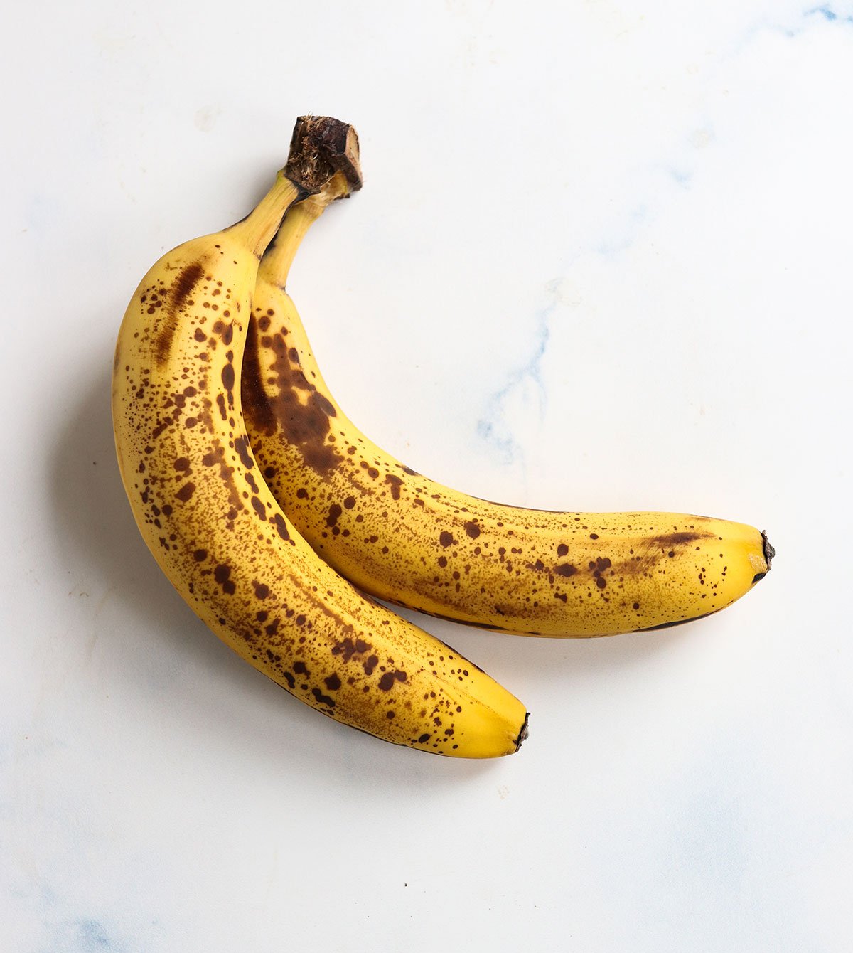 very ripe bananas sitting on a white counter.