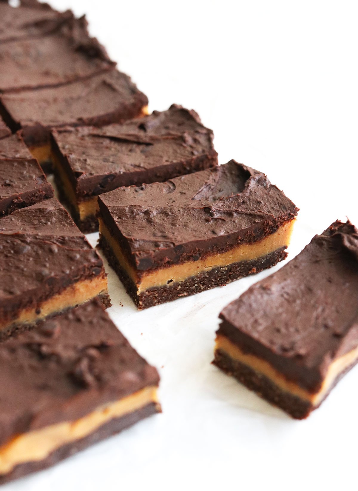 chocolate peanut butter bars sliced on white surface.