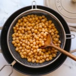 cooked chickpeas from scratch in a strainer over a black pot.