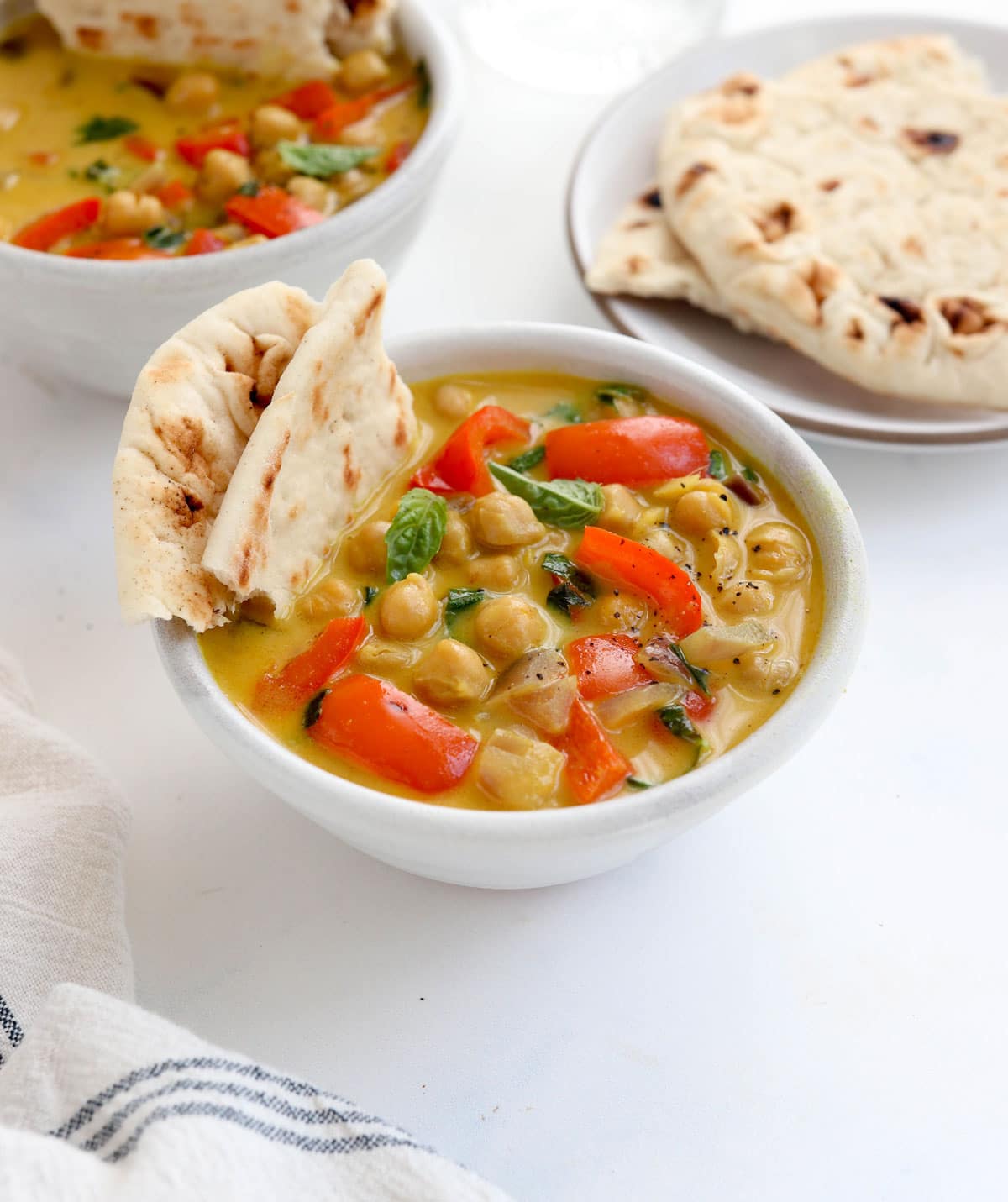 chickpea curry in white bowl with bell peppers