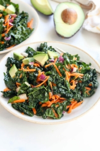 kale salad on white plate with avocado