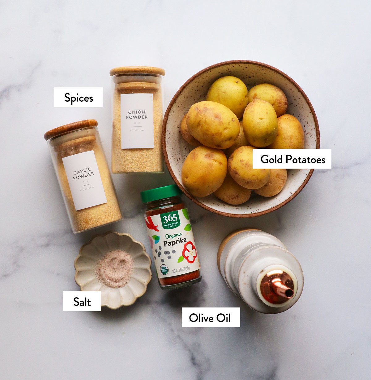 Potatoes, spices and olive oil marked with jars.