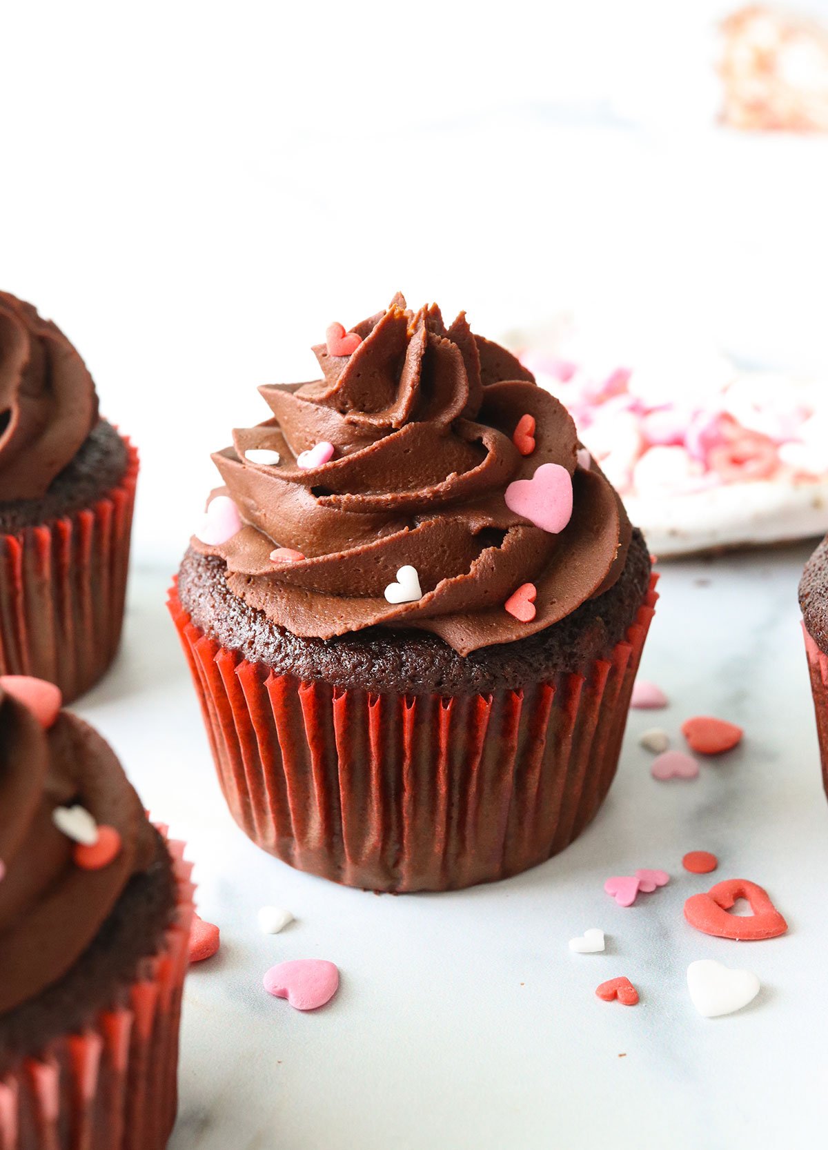 Chocolate almond flour cupcake topped with frosting and heart sprinkles.