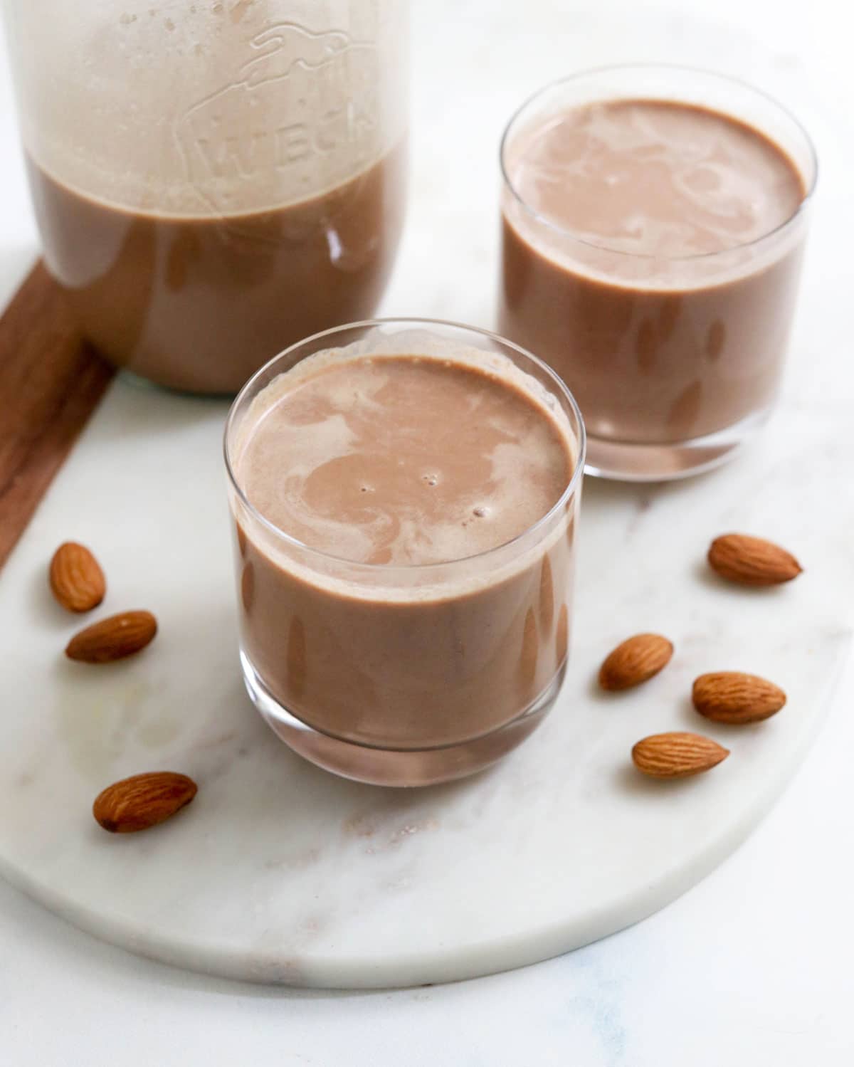 chocolate almond milk in two small glasses with almonds around