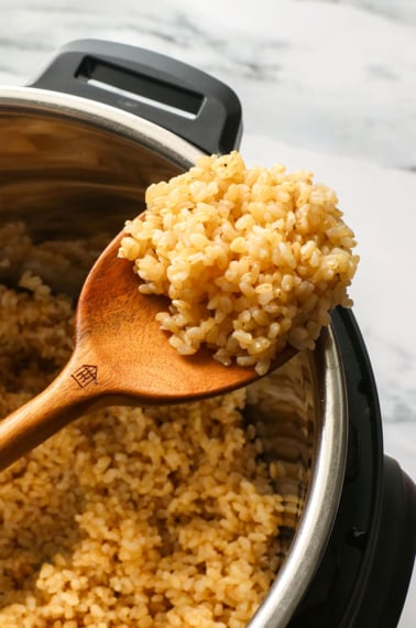 brown rice on a wooden spoon on the Instant Pot.