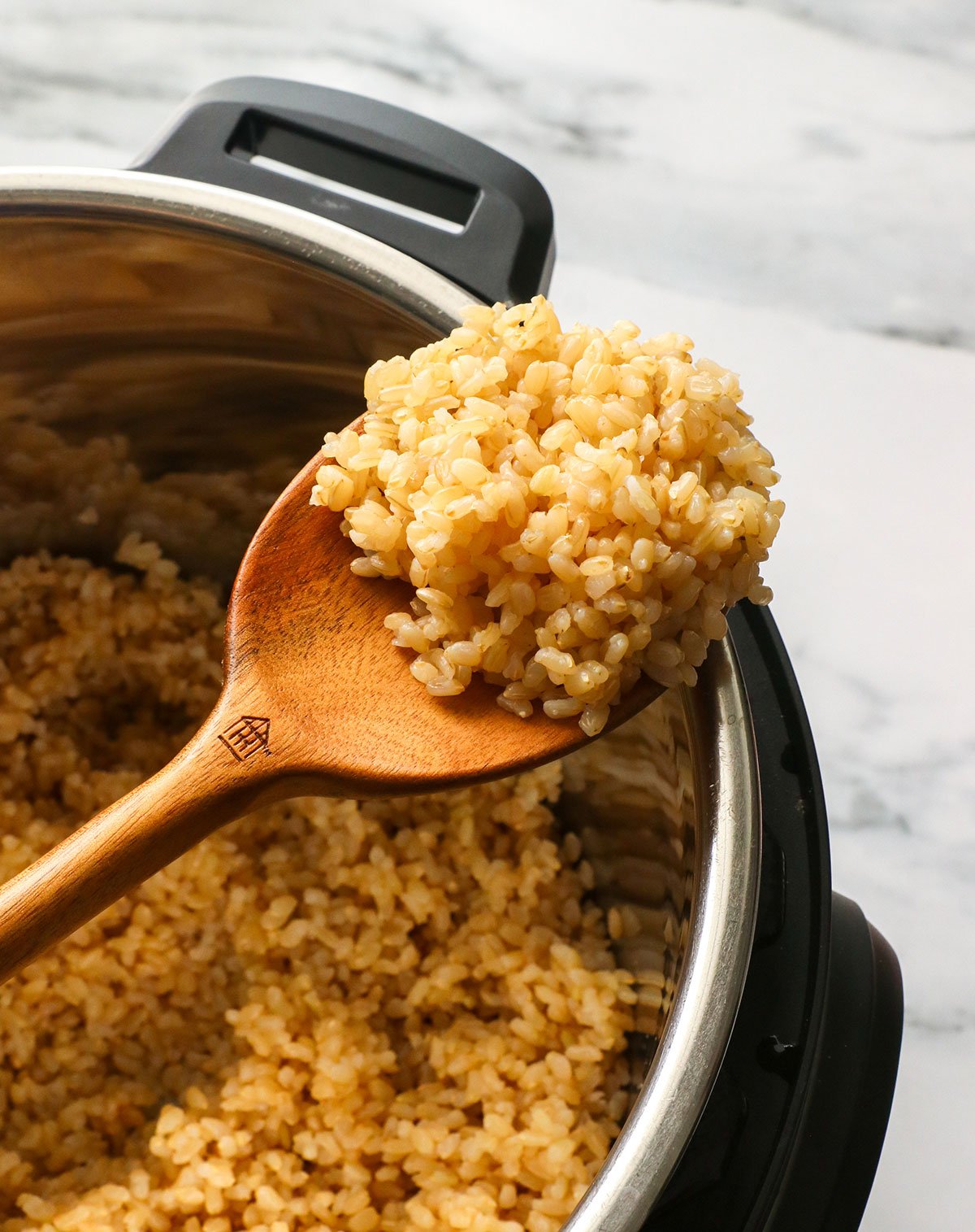 brown rice on a wooden spoon on the Instant Pot. 