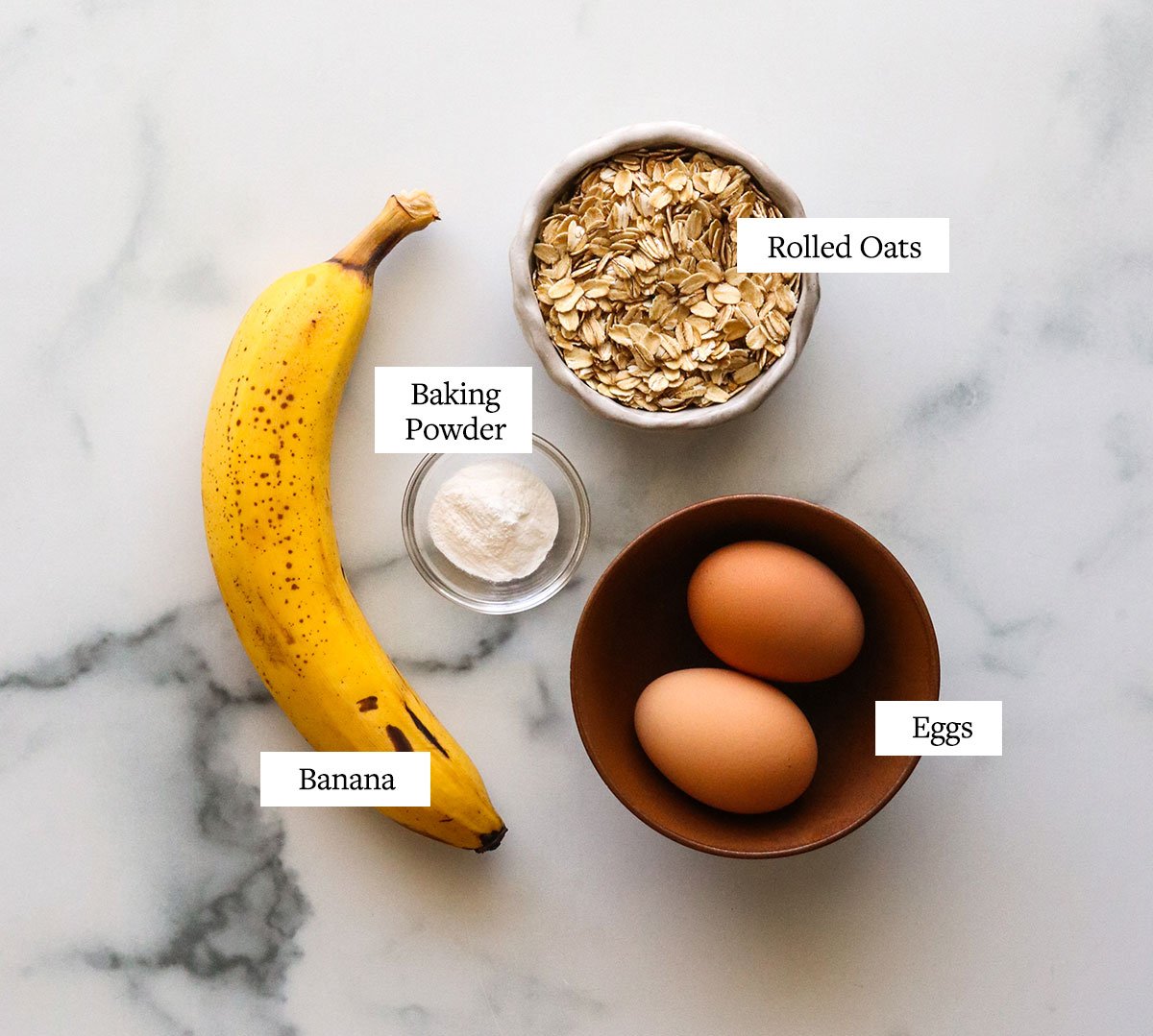 banana egg pancake ingredients labeled on marble surface. 