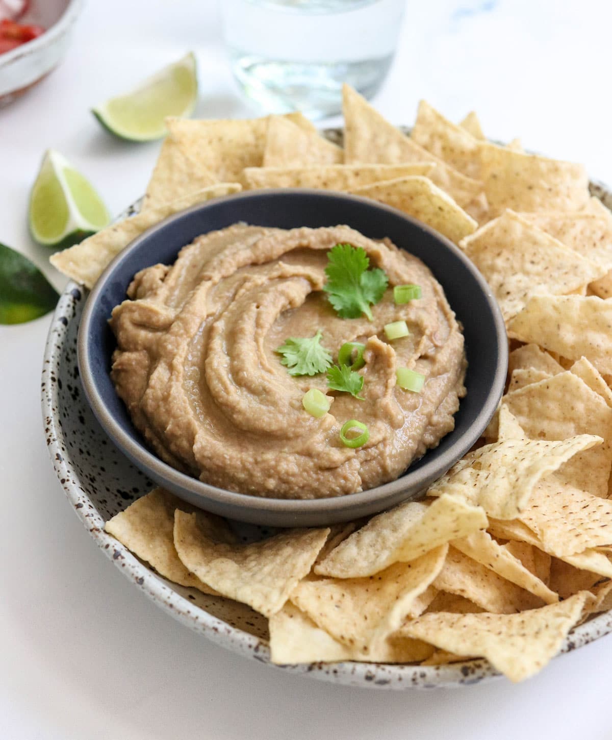 bean dip in a bowl with chips and fresh cilantro