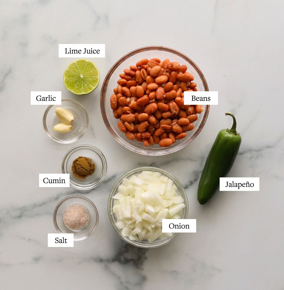 bean dip ingredients labeled on a marble surface.