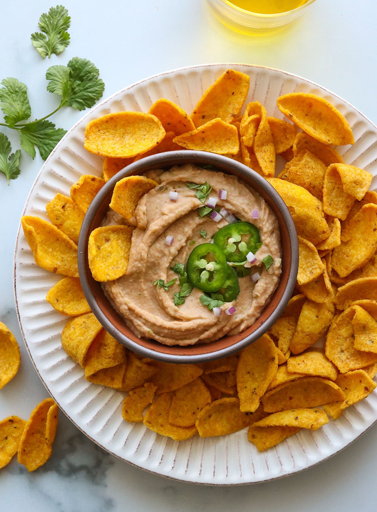 bean dip garnished with jalapenos cilantro and onions.