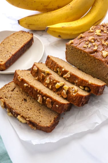 coconut flour banana bread sliced near a bunch of bananas.