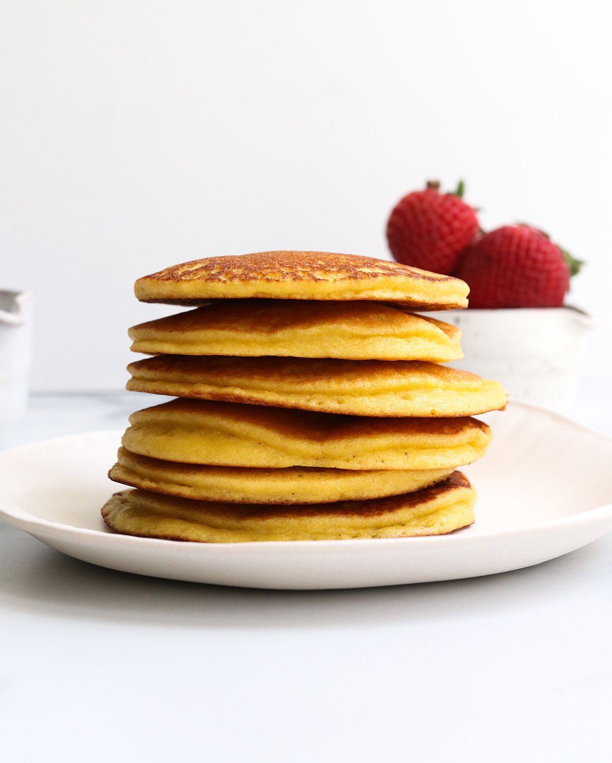 almond flour pancakes stacked on white plate.