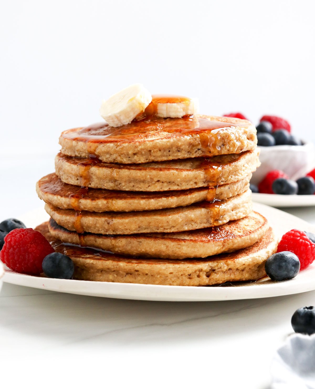 banana oatmeal pancakes stacked with maple syrup on top.