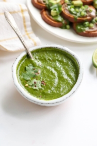 cilantro sauce in a white bowl with spoon