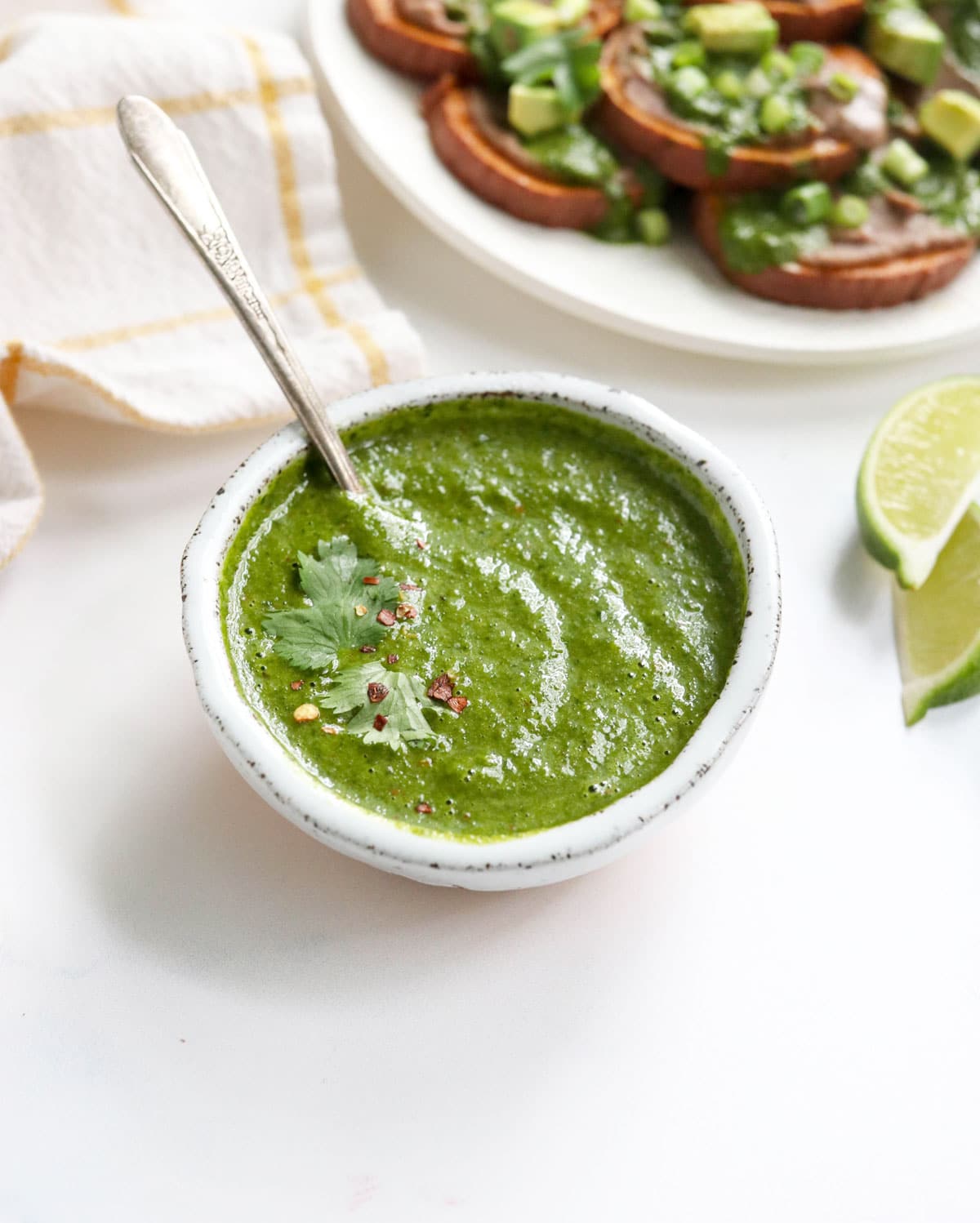 cilantro sauce in a white bowl with spoon