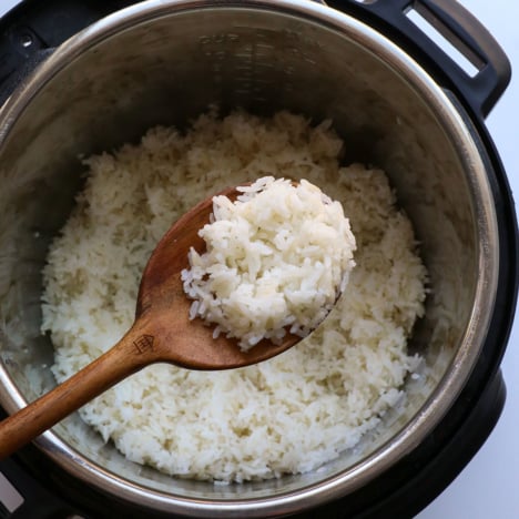 wooden spoon holding white rice over the instant pot.