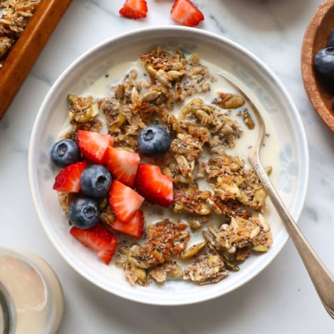 paleo granola served with almond milk and berries in a bowl.