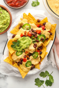 Vegan nachos topped with queso jalapeno slices and guacamole.