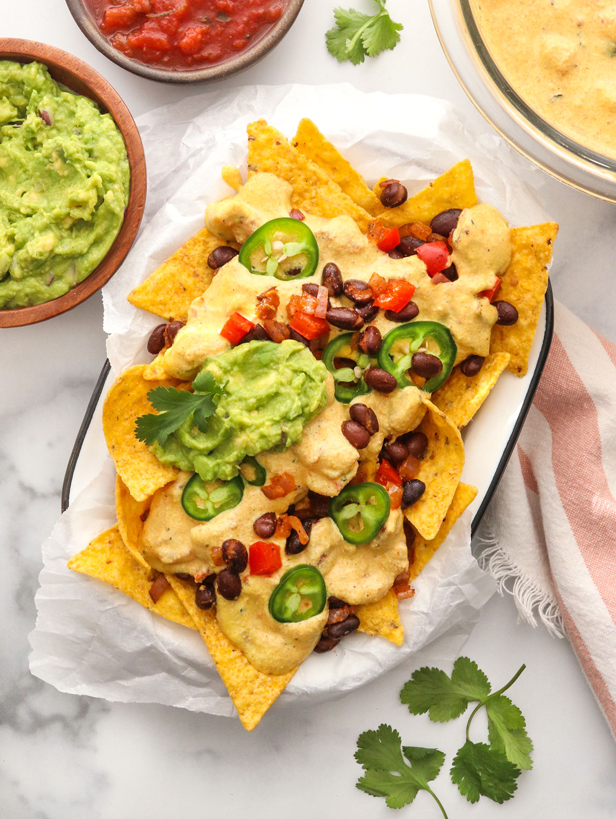 Vegan nachos topped with queso jalapeno slices and guacamole.