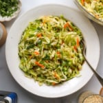 Asian slaw served in a white bowl with a fork.
