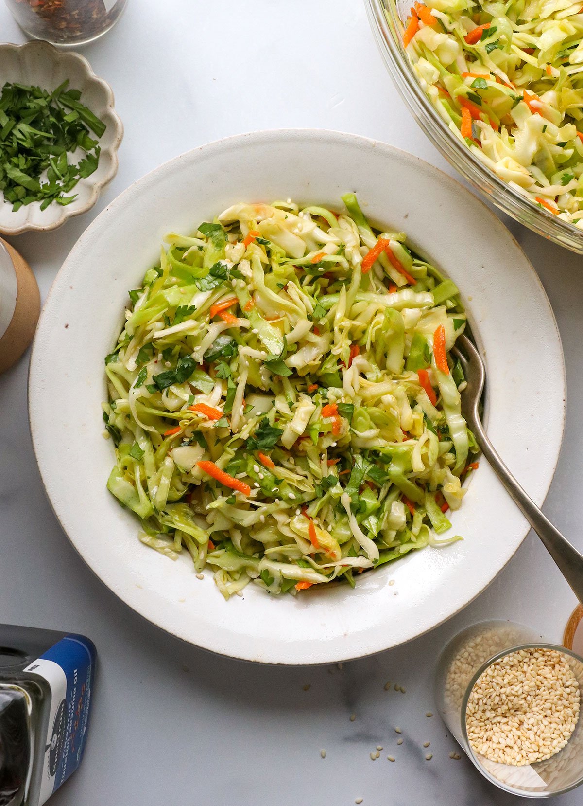 Asian salad served in a white bowl with a fork.
