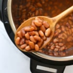 instant pot pinto beans on a spoon resting on the pot.