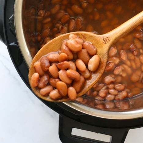 instant pot pinto beans on a spoon resting on the pot.