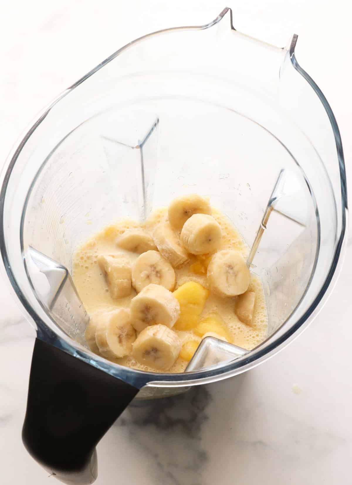 pineapple and frozen banana added to a blender.