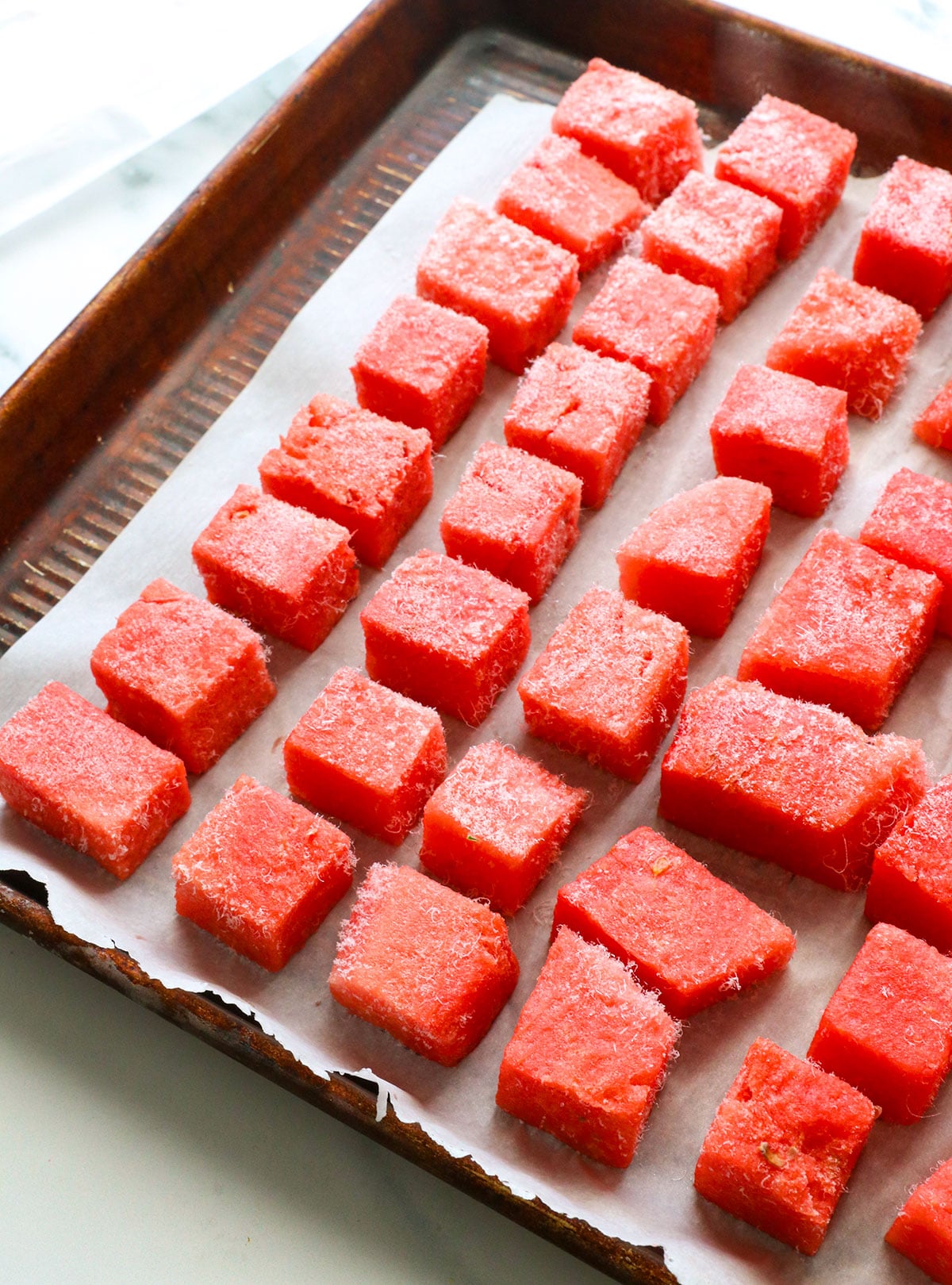 watermelon cubes frozen on a lined baking sheet.