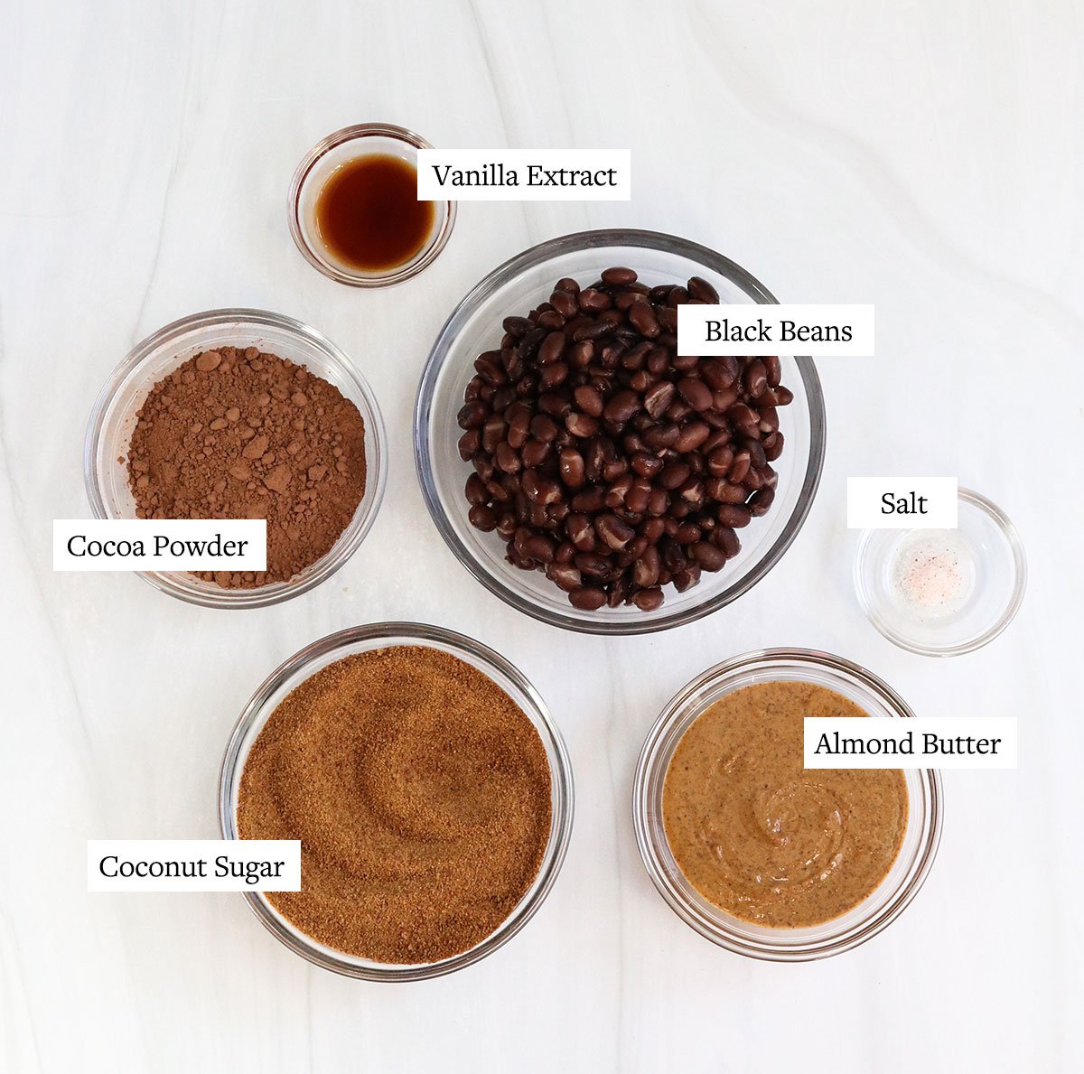 chocolate hummus ingredients labeled in glass bowls.