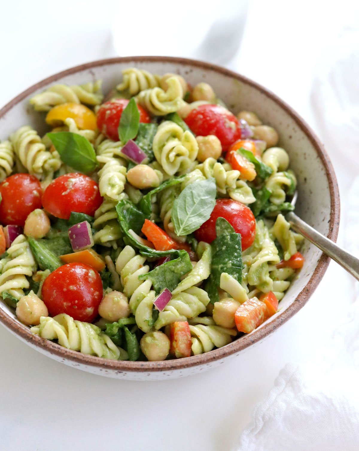 pesto pasta salad in a white bowl with fork