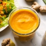 carrot ginger dressing in a glass jar near a salad.