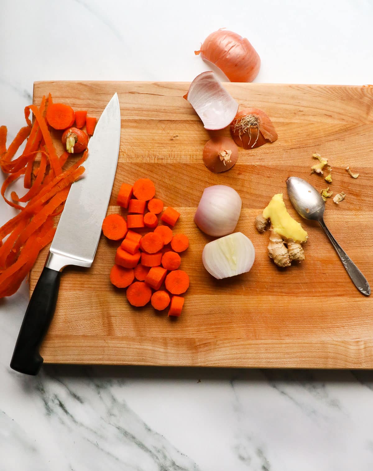 carrots, shallot, and ginger on a cutting board.
