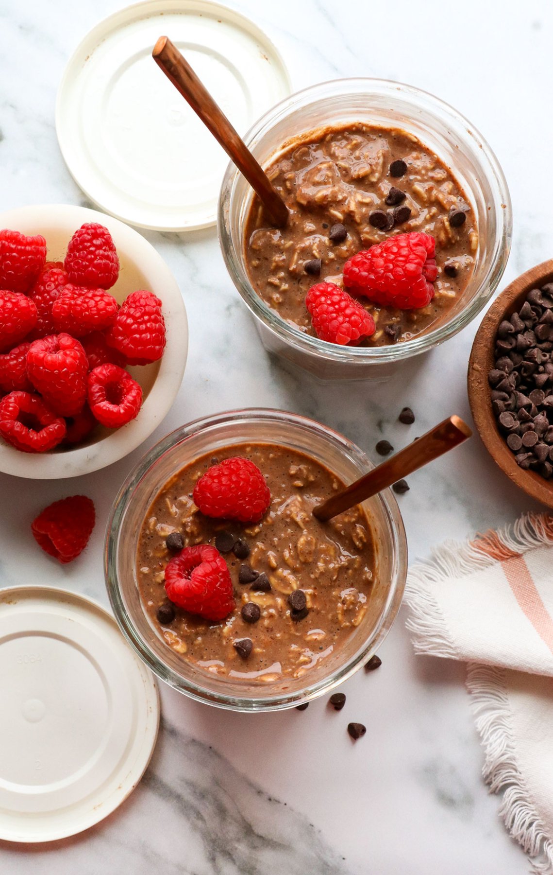 two jars of chocolate overnight oats topped with raspberries.