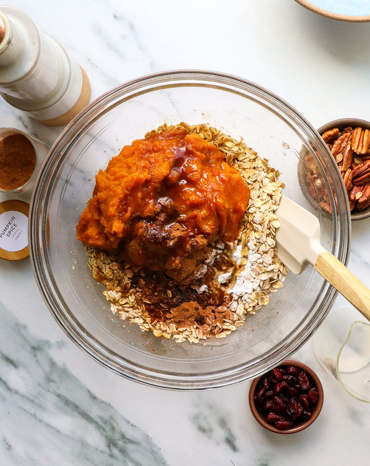 rolled oats, pumpkin, maple syrup, and spices added to a large mixing bowl.