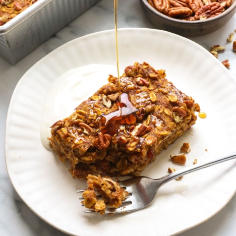 sliced of pumpkin baked oatmeal with maple syrup drizzled on top.