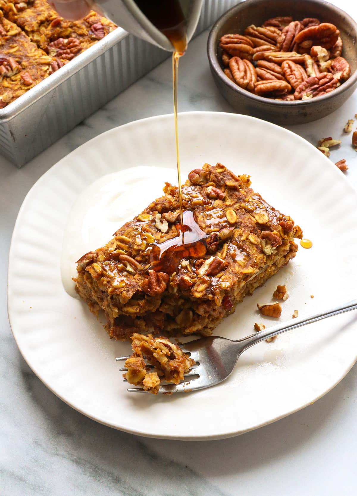 sliced of pumpkin baked oatmeal with maple syrup drizzled on top.