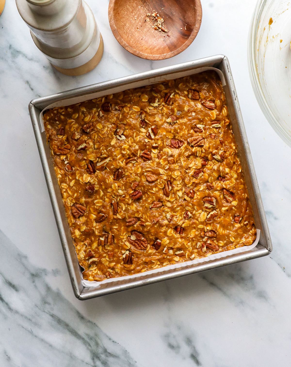 pumpkin oatmeal added to a baking pan with pecans on top.