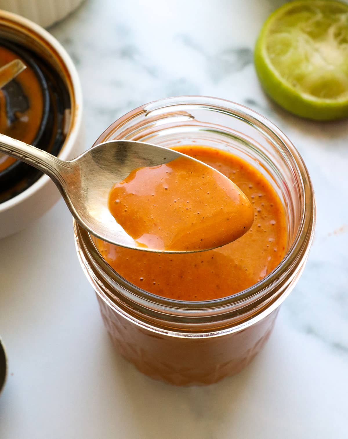 Spoon lifting up chipotle vinaigrette to show the texture.